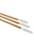 Three gold-colored brushes with bristle heads on a white background